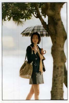 Jacket, skirt, bag by Louis Vuitton, blouse by Chloé, umbrella by Traditional Weatherwear, earrings by Duna