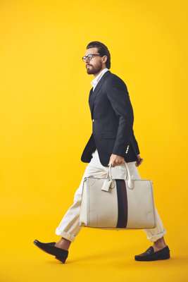 Glasses by Oliver Peoples, jacket by Dunhill, shirt by Black Fleece by Brooks Brothers, trousers by Todd Snyder, shoes by Ralph Lauren, bag by Gucci