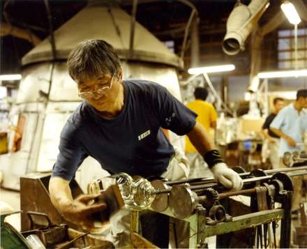 Glass blower checks his work for imperfections