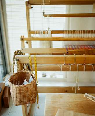 Basket to catch clippings from weaving hangs on one of Sekimachi’s looms