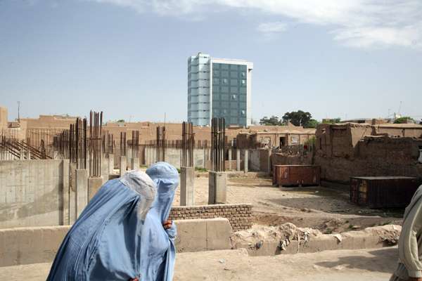 Women in traditional burqas walk past a new office block