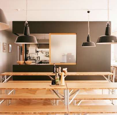 The ground floor kitchen, dining and event space has an oak parquet floor by Bauwerk, an industrial kitchen designed by Andreas Martin-Löf and built by Blumer Schreinerei. Tables and benches were custom-made by Novex and barstools are by Another Country