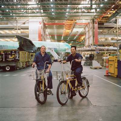 Shad Talbot (left) and Son Ho ride bikes through the Boeing facility
