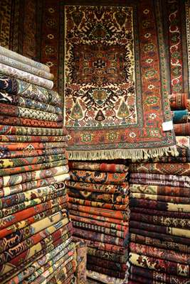 A carpet on top of stacks of fine pieces in the carpet bazaar