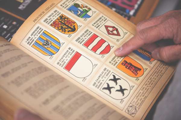 Staff flip through a vintage book of Dutch crests for new ideas 