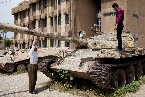 Kurdish men play on tanks that were captured by Kurdish guerillas in 1991