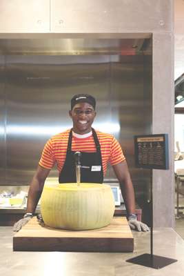 An employee about to crack into a wheel of Parmesan