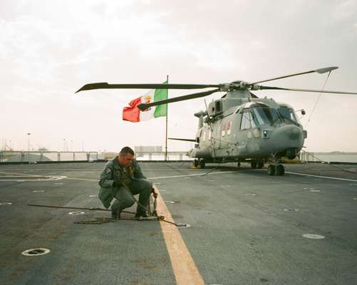 Flight deck crewman removes cable used to secure aircraft