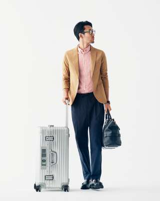 Jacket by Ships, shirt by Steven Alan, trousers by Undecorated Man, shoes by Paraboot, glasses by Ray-Ban, watch by Vacheron Constantin, suitcase by Rimowa, bag by Bally 