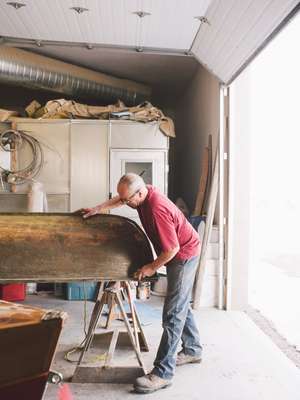 Scraping dirt off an old canoe ready to refurbish