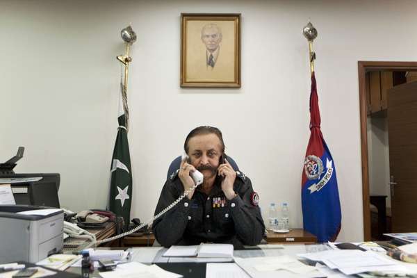 Waseem Ahmed, Karachi chief of police, talks on his landline and mobile phone in his office 