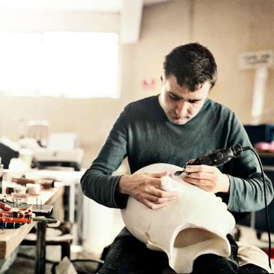 An assistant works on a puppet head for a television series