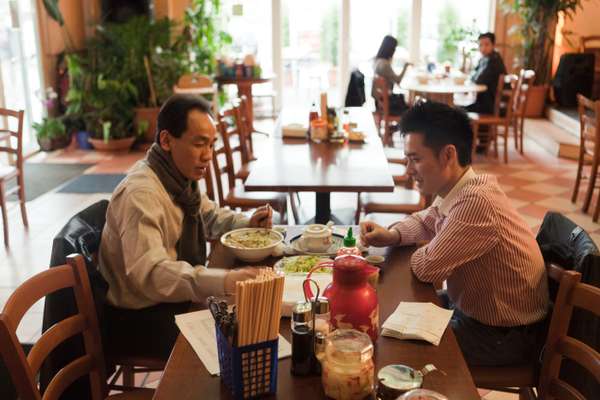 Nquyen Kien Coung (left), who runs a snack bar, and Cu Huu Viet, who works at a food market, have lunch at Dong Xuan Center
