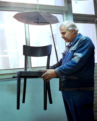 Worker applying varnish to a chair