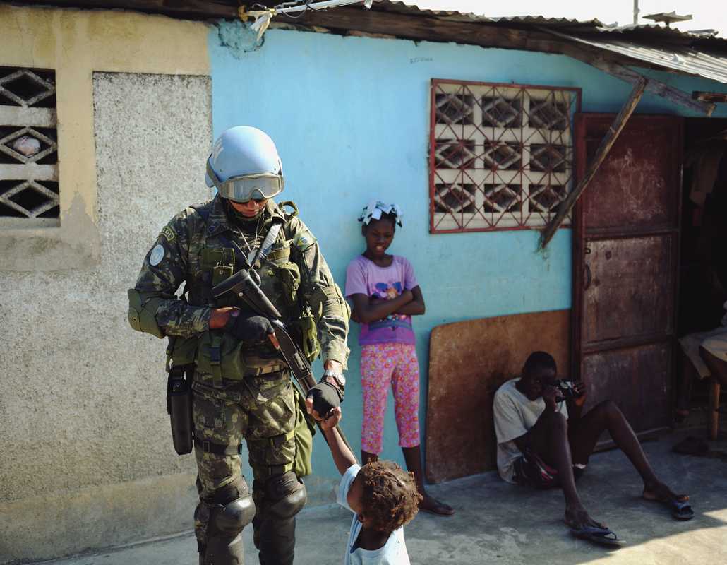 Brazilian soldiers bump fists with children in Cité Soleil