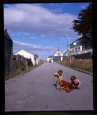 Children at play outside a peat hut on Allardyce Street, Stanley