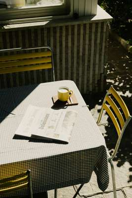 A morning newspaper read on Swiss outdoor café furniture by Manufakt 