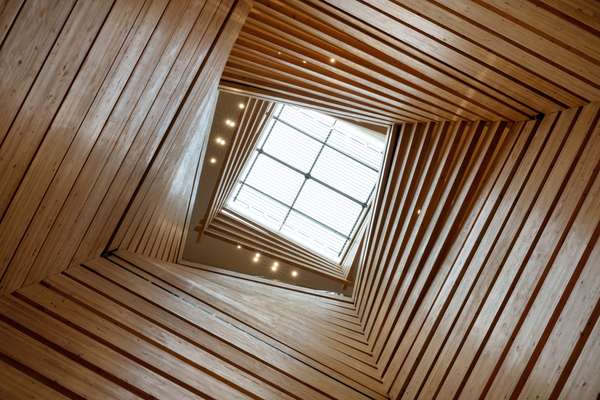 Light filters through an undulating timber chimney