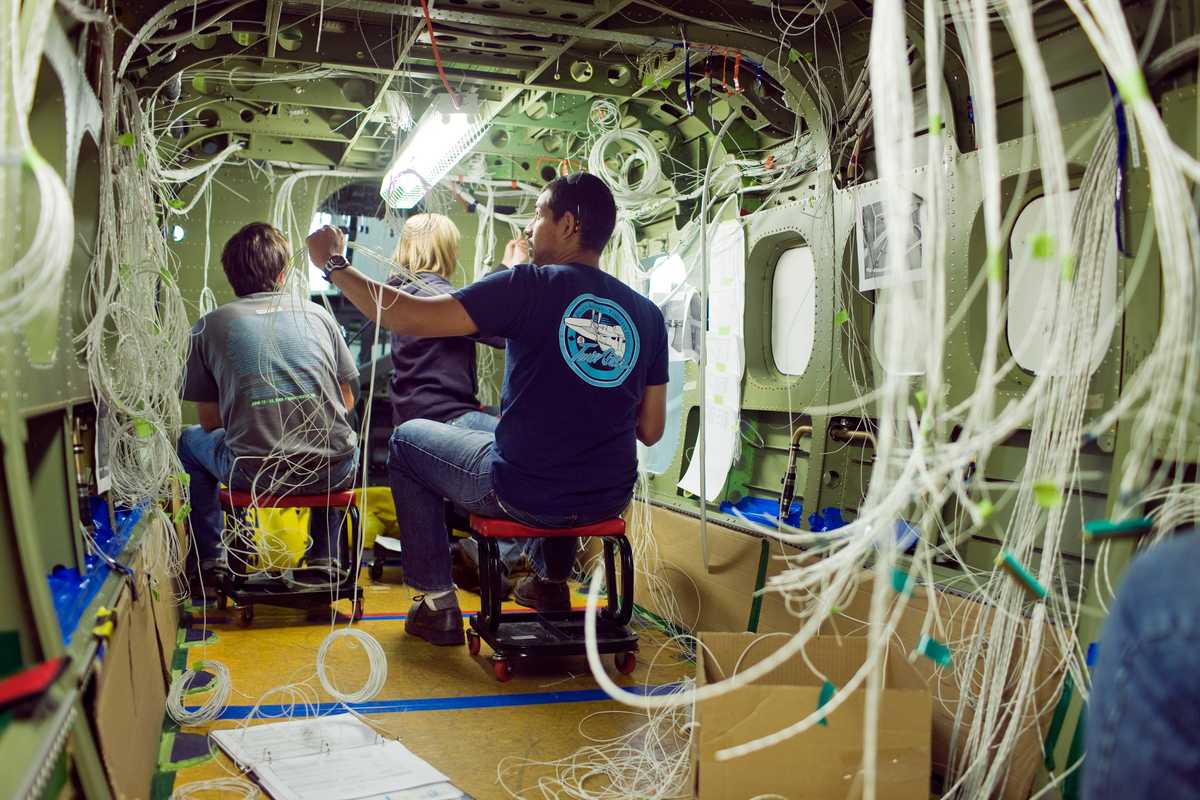 Viking Air employees stringing wires through the chassis of a Twin Otter 