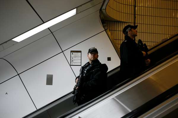 Firearms officers ascend an escalator from Gatwick station to the airport