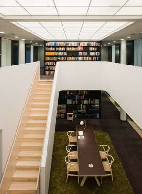 A white Gypsum barrier sweeps around the opening between the library's two floors, which are linked by a staircase in white stained ash.