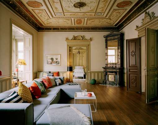 Collste’s living room with restored floorboards and handpainted ceiling, softened with a scattering of Svenskt Tenn cushions. At the far end is her daughter’s bedroom