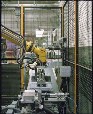 A robot drops cases onto the quality control and packaging line