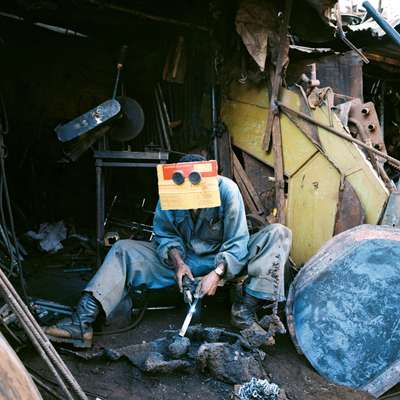 Ghilom Tesfamichael wears goggles and a piece of cardboard while welding at Medeber market 