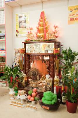 Buddhist shrine in Nguyen Thi Ha’s store with offerings including fruit and alcohol
