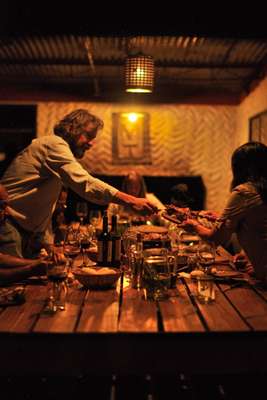 Host Soriano serving dinner to guests sharing a  long table