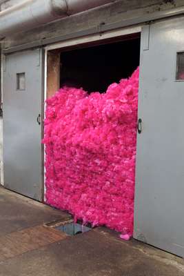 Multiple colours of dyed wool are blown through overhead tubes into a room called a blending bin where the colours are combined 