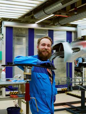 Smiling staff manually check painted parts for blemishes