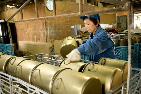 Worker preparing steel containers for enamelling