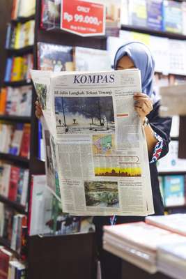 Indonesian woman reading ‘Kompas’ in the bookshop at Soekarno–Hatta International Airport