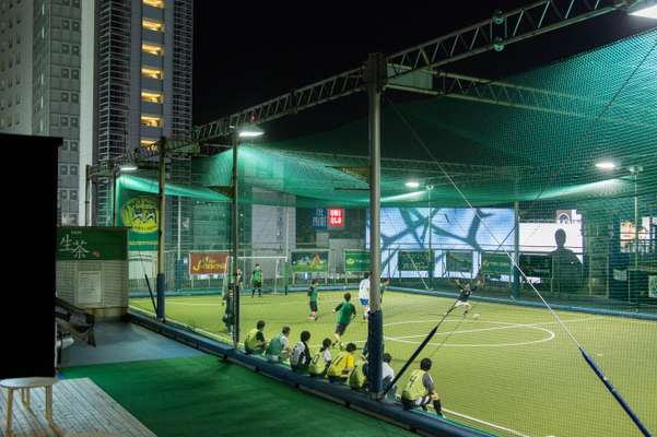 Futsal and floodlights set against the cityscape