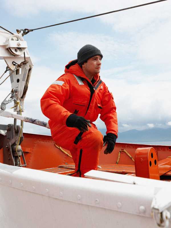 A crew member dons a float suit for a safety drill