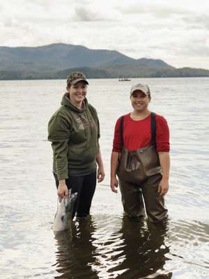 Women in hip waders clean fresh-caught salmon
