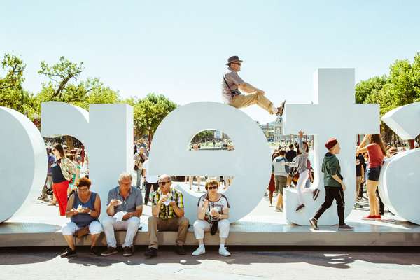 Tourists sit beside (and atop) the IAMsterdam sign outside the Rijksmuseum