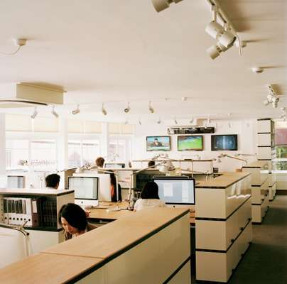 The Monocle office has oak-topped desks and shelving by Novex, Tolomeo task lamps by Artemide and carpets by Tisca Tiara. Panasonic televisions keep staff updated with breaking news. Walls of original windows on both sides of the office provide plenty of daylight and a through draft when open 