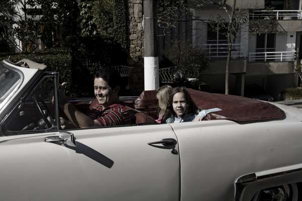 A father drives his family in a 1950s Plymouth car