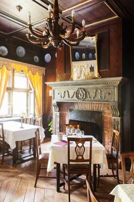 Tuscan fireplace and wooden chandelier in dining room