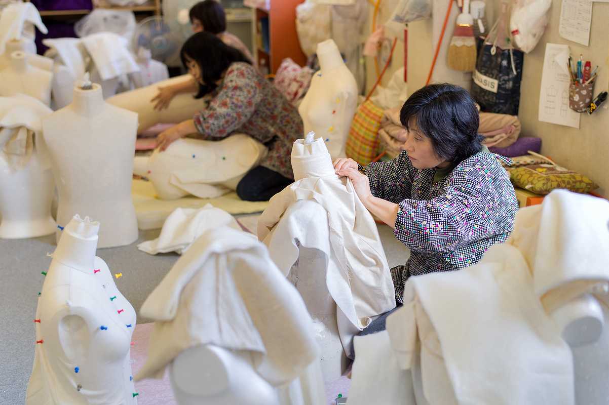 Zama employee stitching pattern-cut cloth onto a  mannequin to finish it off