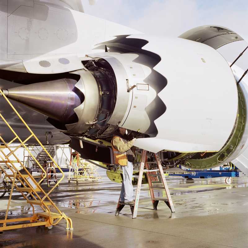 A technician works on a GEnx-2B engine of a nearly completed 747-8 on the flight line