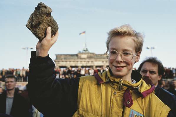 10 November 1989: a bystander holds a souvenir chunk of masonry from the Berlin Wall the day after it fell