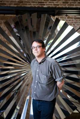 Andrew Ignarski stands in front of an Anish Kapoor work