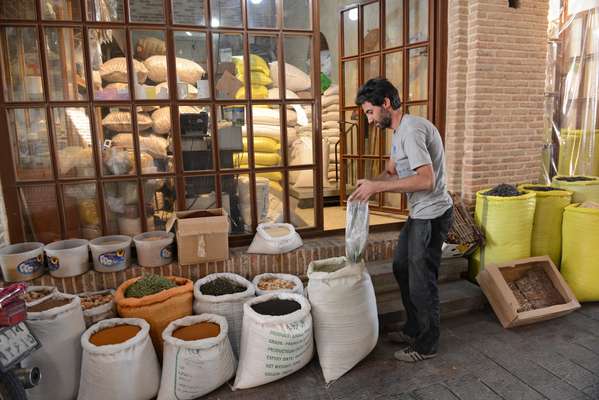 A man puts herbs inside a plastic bag outside a spices shop 