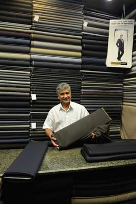 Mohammad Rezai stands in his small shop selling fabrics for men’s suits