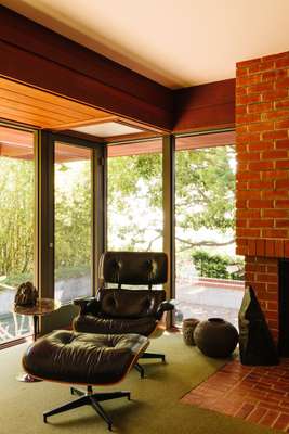 Vintage Eames Lounge Chair beside the indoor-outdoor fireplace in the study 
