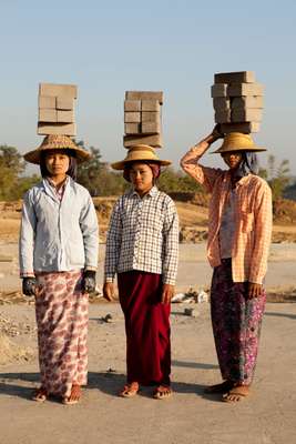 Construction workers balancing bricks on their heads