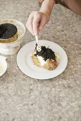Adding American Transmontanus caviar to crème fraîche on a baked potato